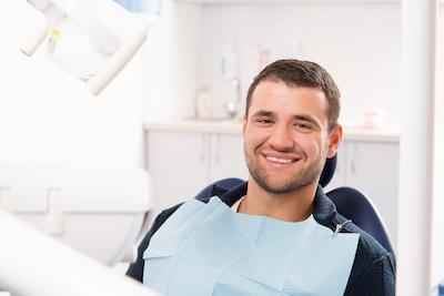 Man smiling in dental chair, fishers in